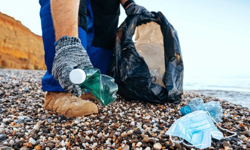 41983536_hand-of-a-man-volunteer-grabbing-plastic-litter-into-a-waste-bag-cleaning-up-the-beach-(1)