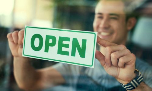 45251540_were-open-cropped-shot-of-a-young-man-hanging-the-open-sign-in-his-coffee-shop-window